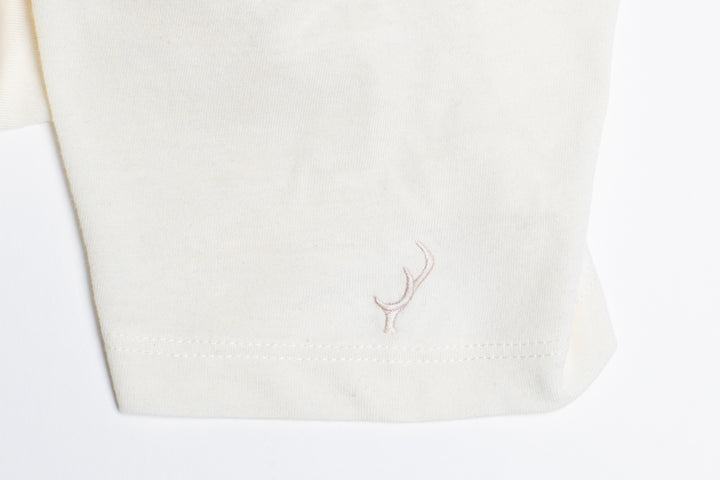 Close-up of Pladra Women’s V-Neck Tri-Blend Tee in Marshmallow White Heather with subtle hem embroidery.