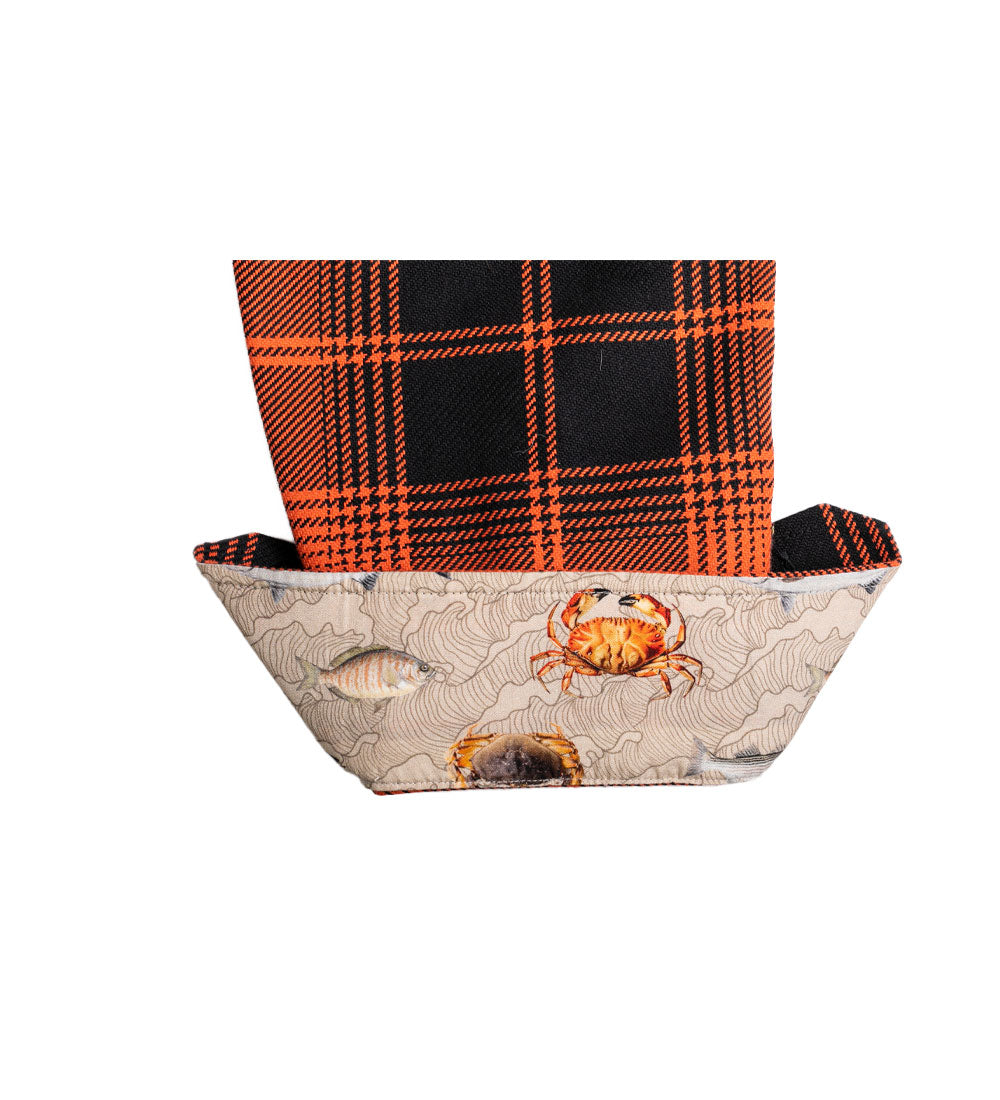 A fabric origami boat with a beige base showing fish and crabs, featuring a folded sail made from an orange and black Women's Leon Workhorse Flannel Shirt- October Orange, inspired by classic heavyweight flannel.