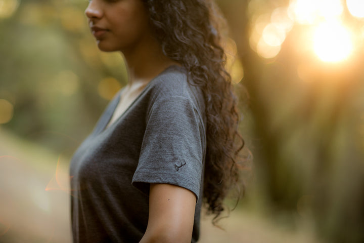 A woman with long, curly hair stands outdoors in a Women&