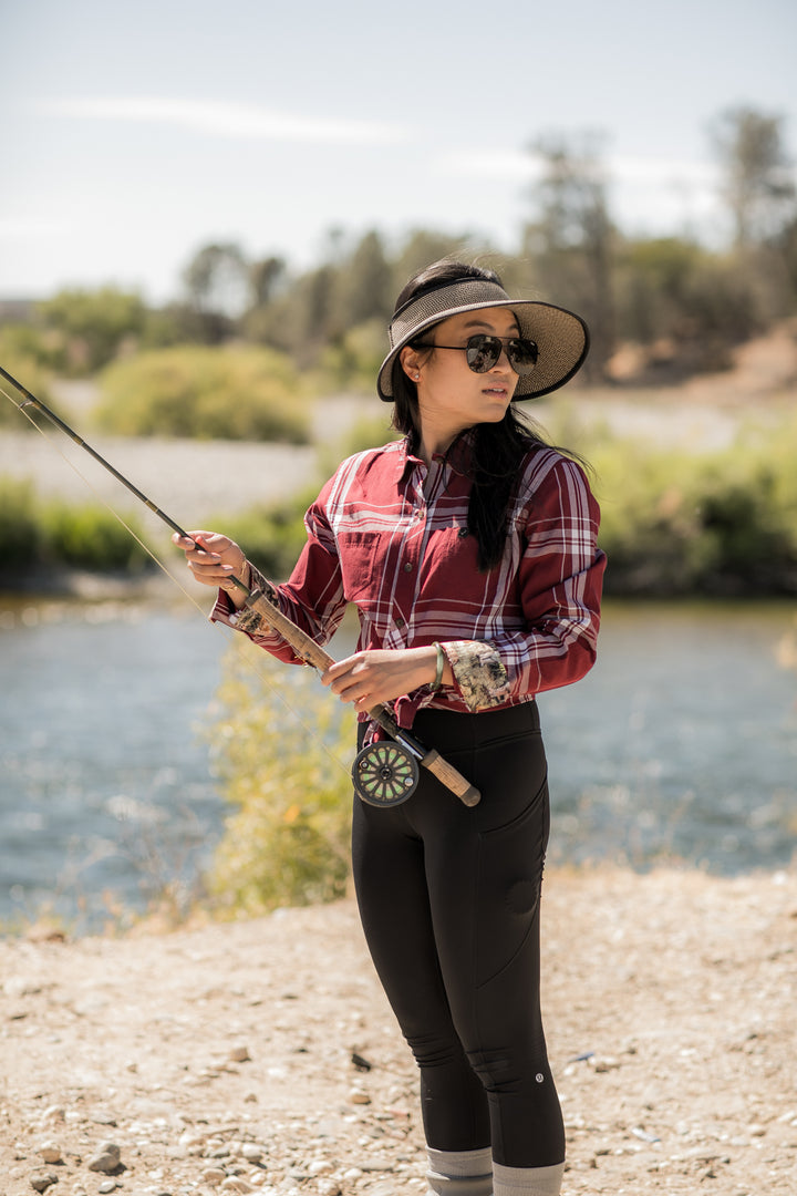 A woman wearing a sun hat, sunglasses, black pants, and the Women&