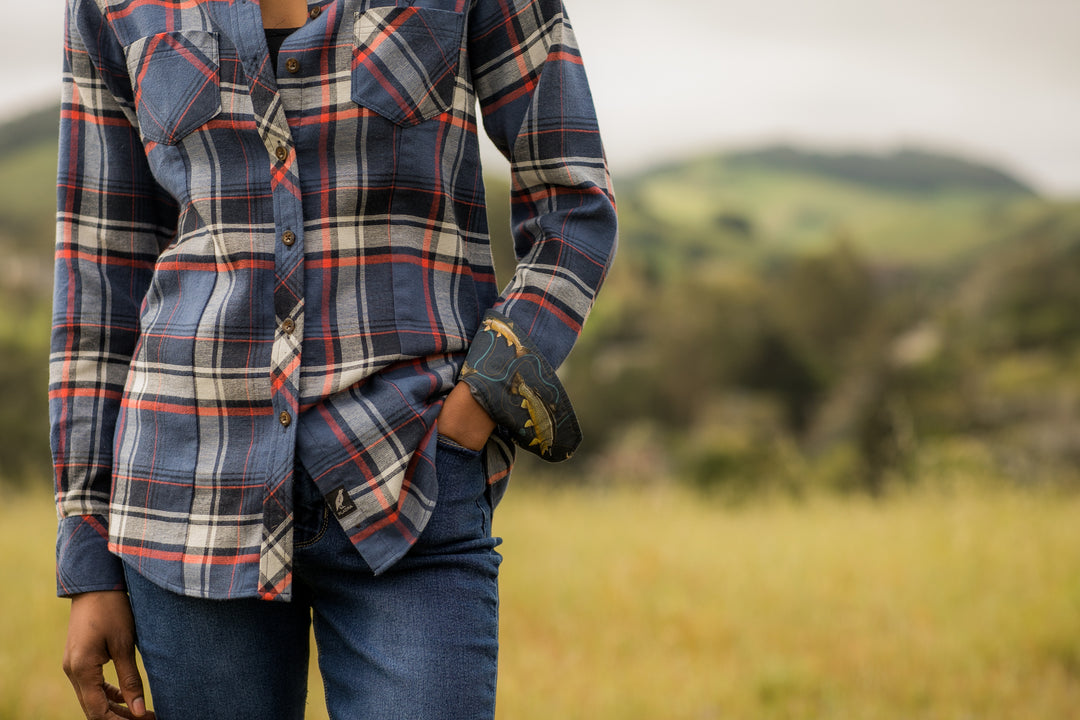 A woman stands in a grassy field wearing the Women&