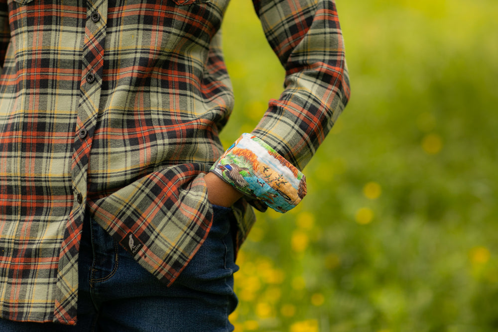 A woman in a Pladra Women's Every Day Double Weave Shirt - Sea Foam Green stands outdoors in a green and yellow field.
