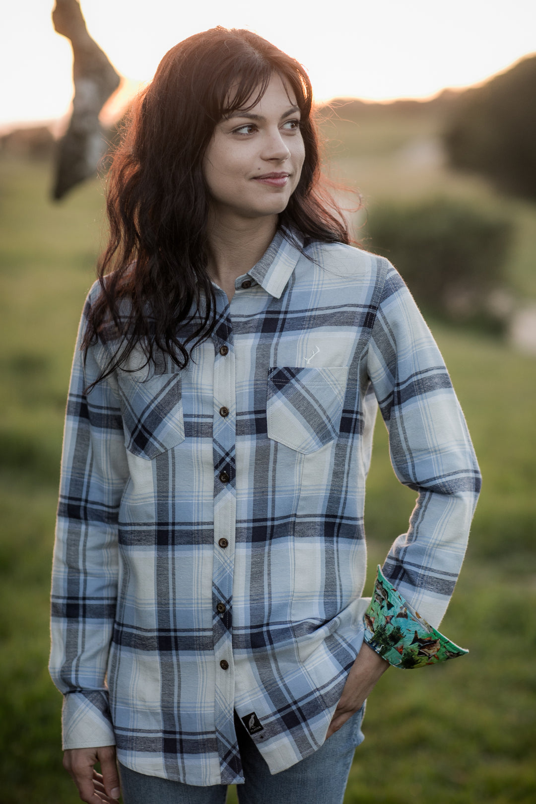 Woman in Pladra’s Women’s Every Day Double Weave Shirt in Birch White stands outside at sunset, looking to the side.