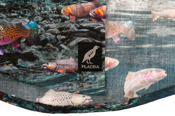 Close-up of Pladra Toddler Cubs Printed Shirt-Trout fabric and black Pladra tag with bird logo.