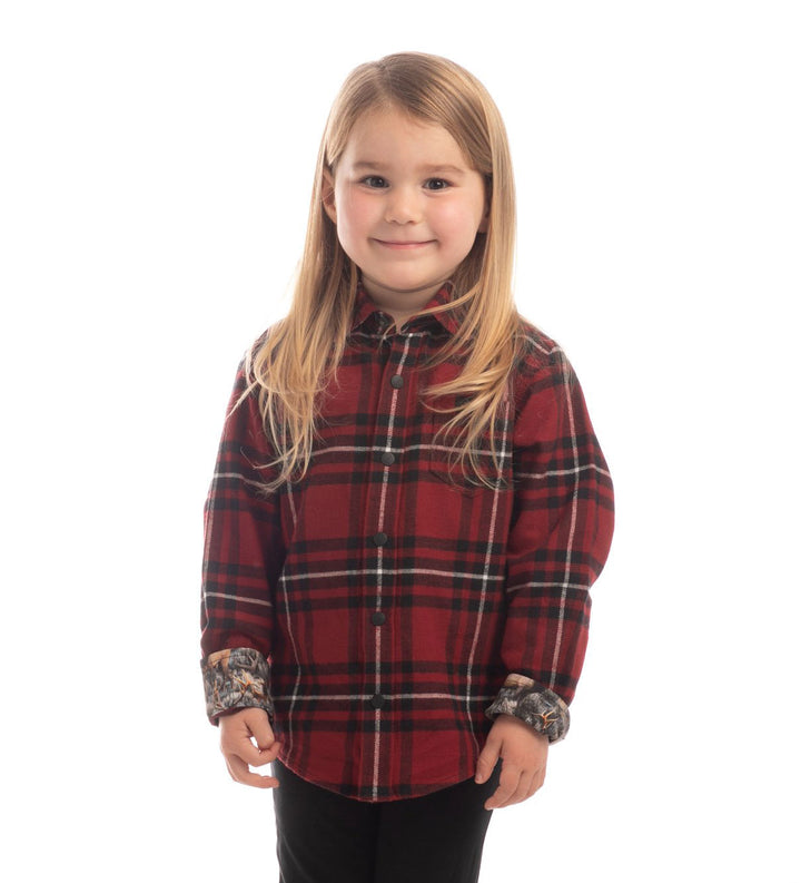 A young child with long blonde hair, dressed in the Toddler Cubs Flannel Shirt- Rocky Red in red and black plaid and black pants, smiles against a white background.