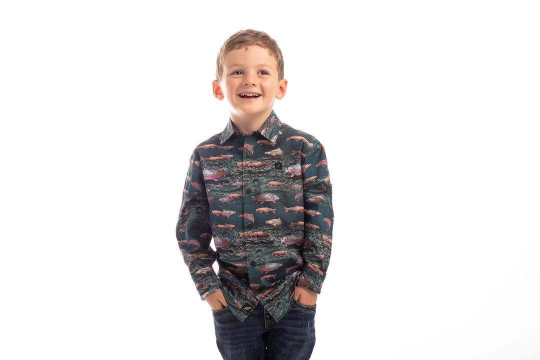 Smiling boy wears the Pladra Toddler Cubs Printed Shirt-Trout and jeans, hands in pockets, against a white background.