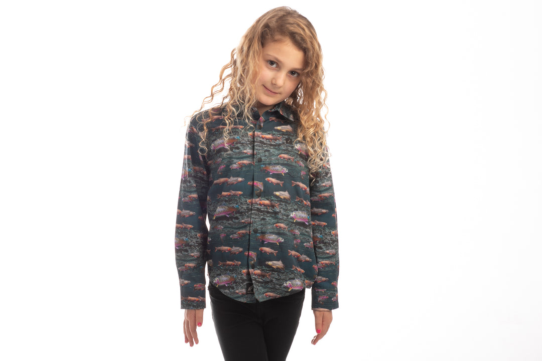 Young girl with curly blonde hair wears Pladra Toddler Cubs Printed Shirt-Trout and black pants against a white background.