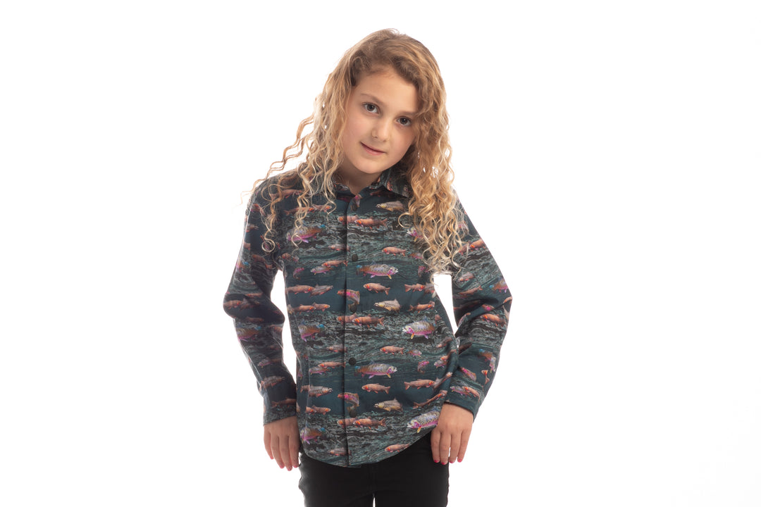 Toddler with long curly hair wears a Pladra Toddler Cubs Printed Shirt - Trout, standing against a white background.