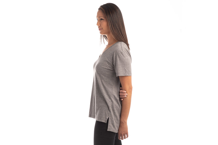 A woman with straight brown hair stands in profile against a white background, wearing a Women&