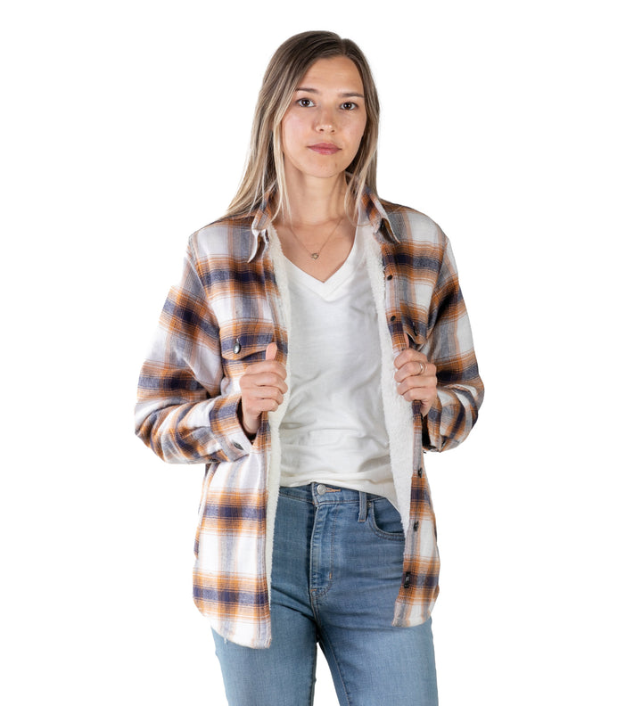 Woman in a Pladra Northwood Sherpa Insulated Flannel Jacket over a white tee and jeans stands against a white backdrop.